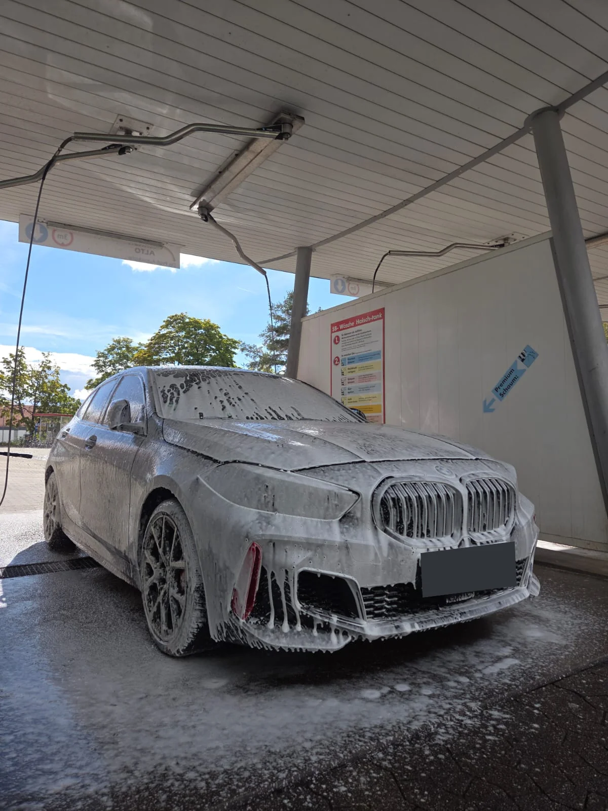 Eingeschäumter schwarzer BMW während der Fahrzeugwäsche und Schaumpflege