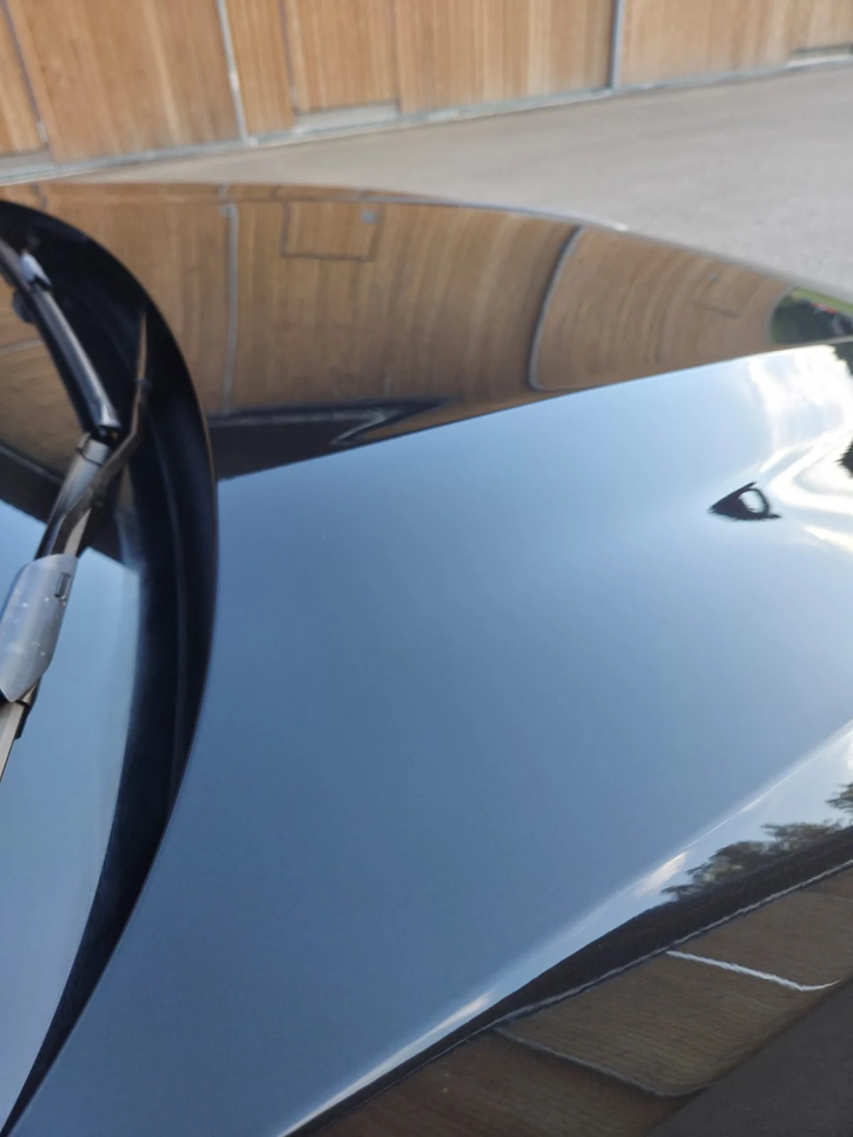Nahaufnahme einer polierten schwarzen Motorhaube mit klaren Reflexionen nach der Lackaufbereitung